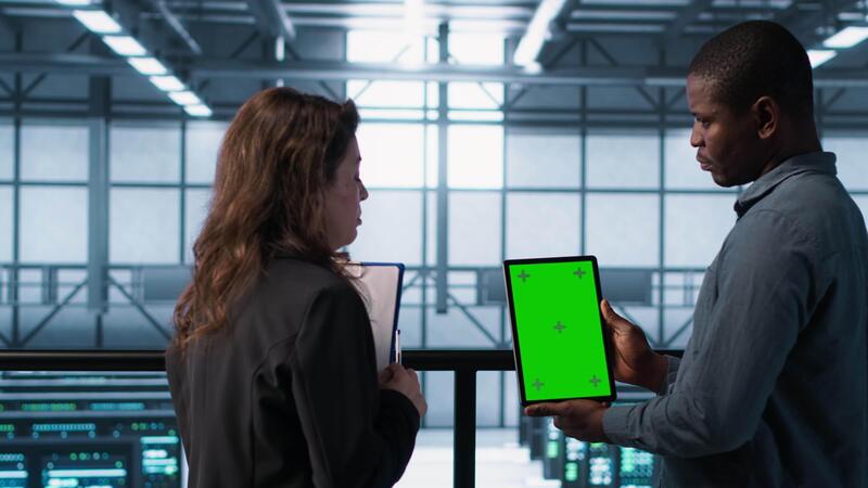 Developer looking at performance graph on computer - Software developers in data center using mockup tablet, observing ...